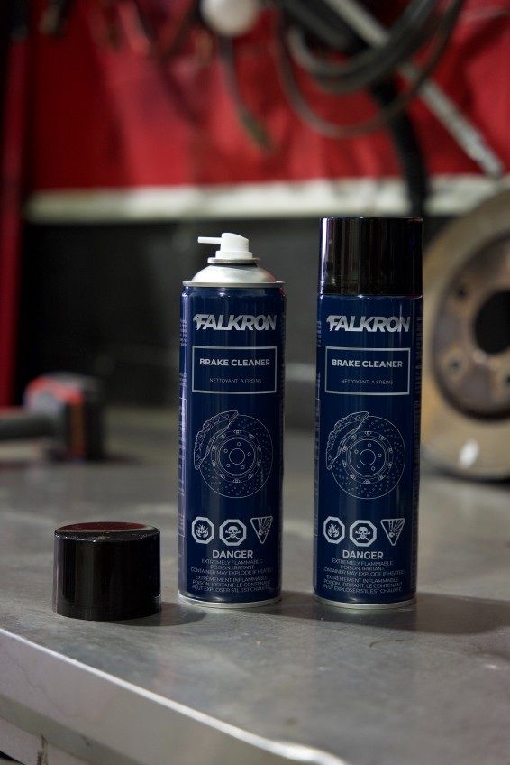 Two cans of FALKRON Brake Cleaner on a steel workbench in a workshop, one with its cap removed